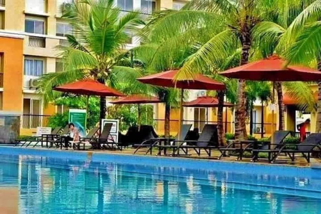 塔里萨伊2BR Casa Mia Sanremo Oasis Cebu的酒店旁的游泳池配有椅子和遮阳伞