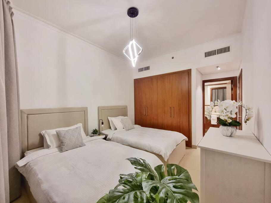 迪拜Spectacular Downtown Apartment T1-34的一间卧室设有两张床和盆栽植物