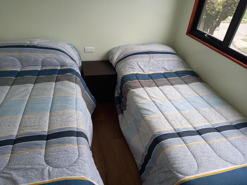 特木科Cabañas y Departamentos Las Palmas, Temuco Depto 1的两张睡床彼此相邻,位于一个房间里