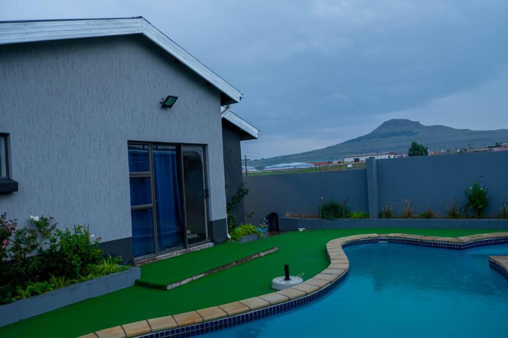 马塞卢K4 Bed and Breakfast的一个带游泳池和房子的庭院