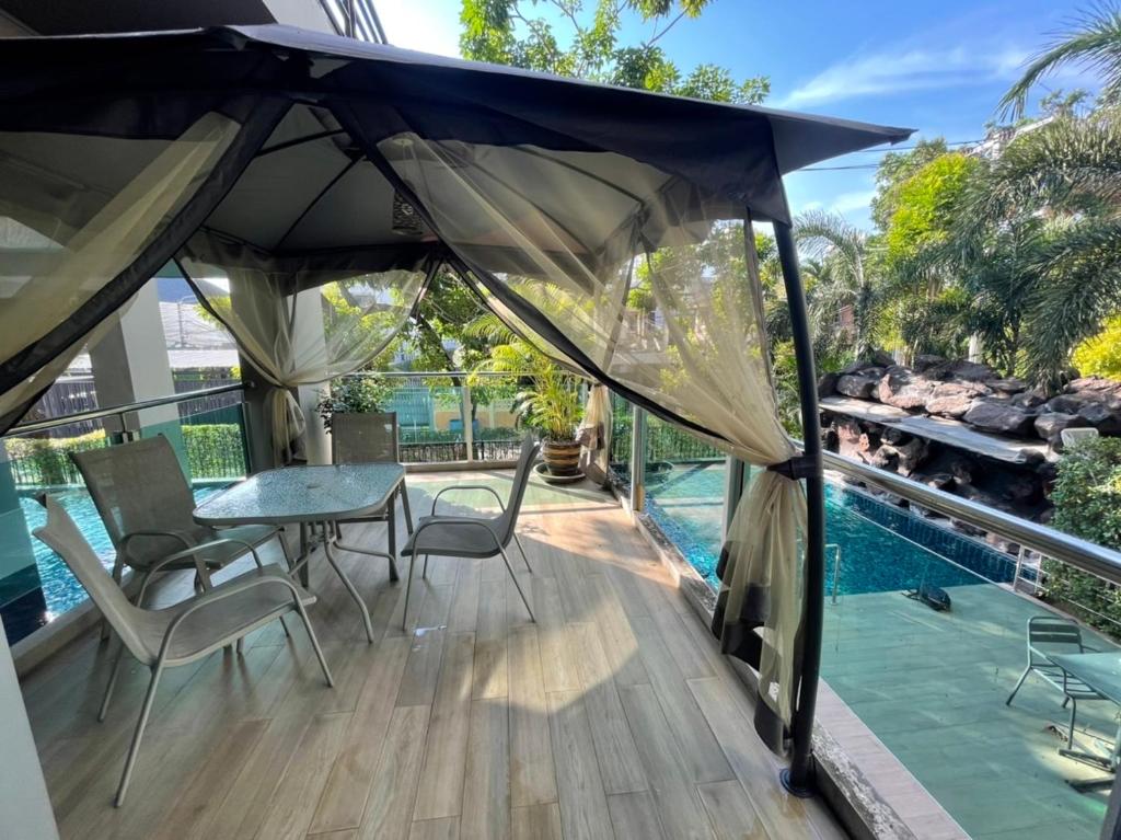 曼谷The Lux Ladprao 10的庭院配有桌椅和遮阳伞。