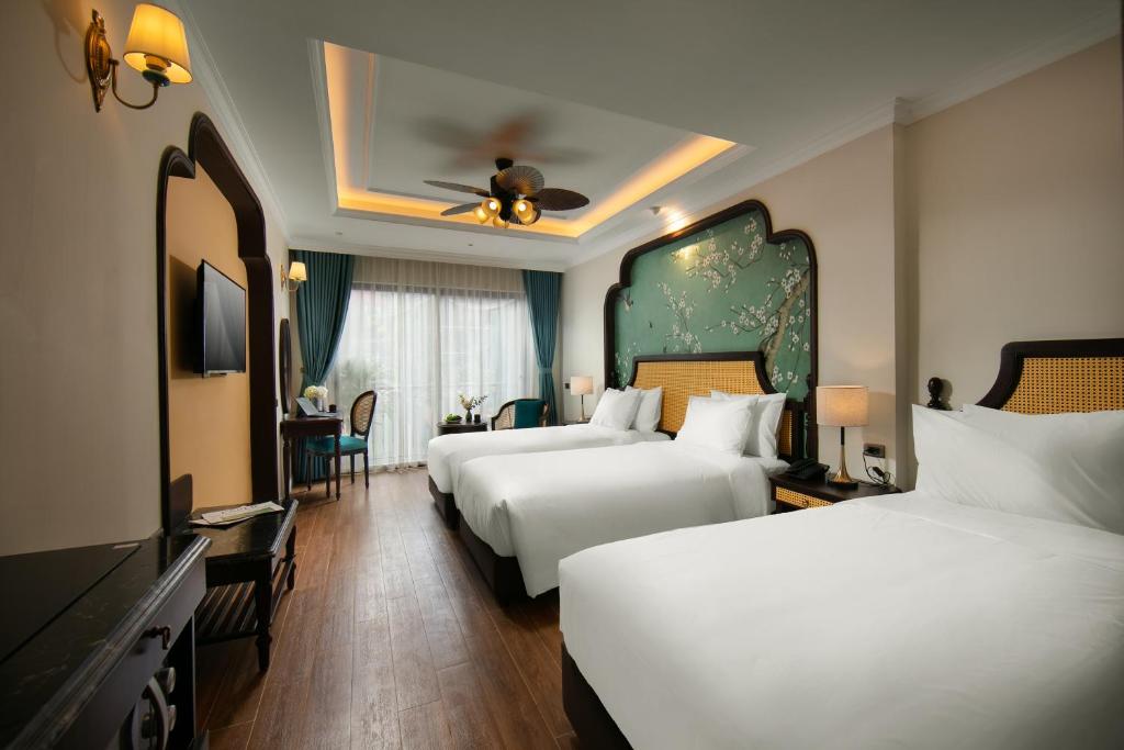 河内La Passion Hanoi Hotel & Apartment的酒店客房设有两张床和电视。