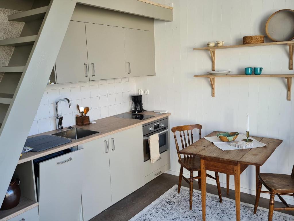 瓦尔贝里Minihuset nära havet的厨房配有白色橱柜和木桌