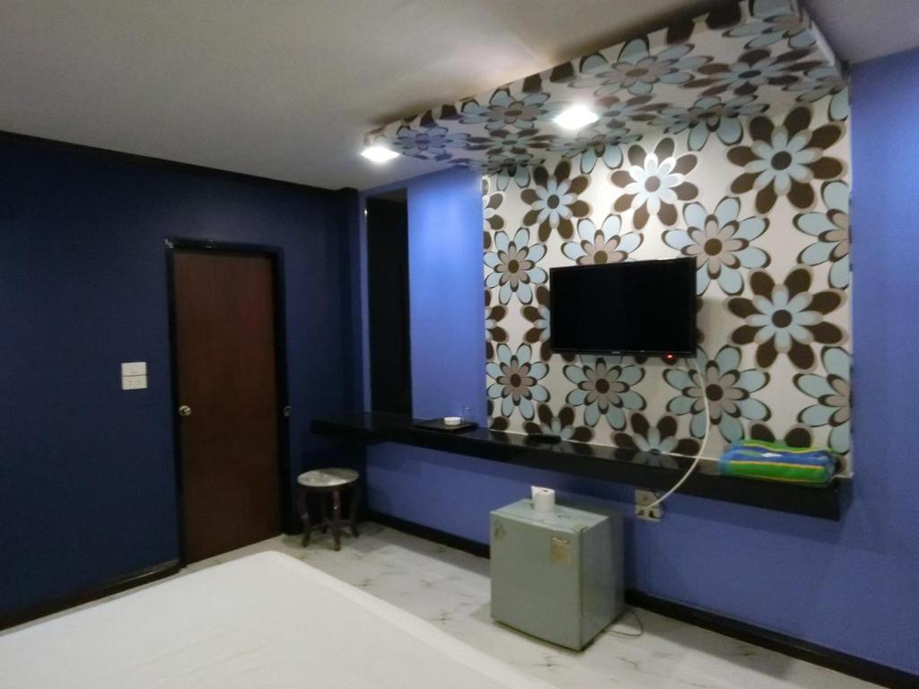 Ban KoNewYork Suite Hotel的一间设有蓝色墙壁的客房,配有电视