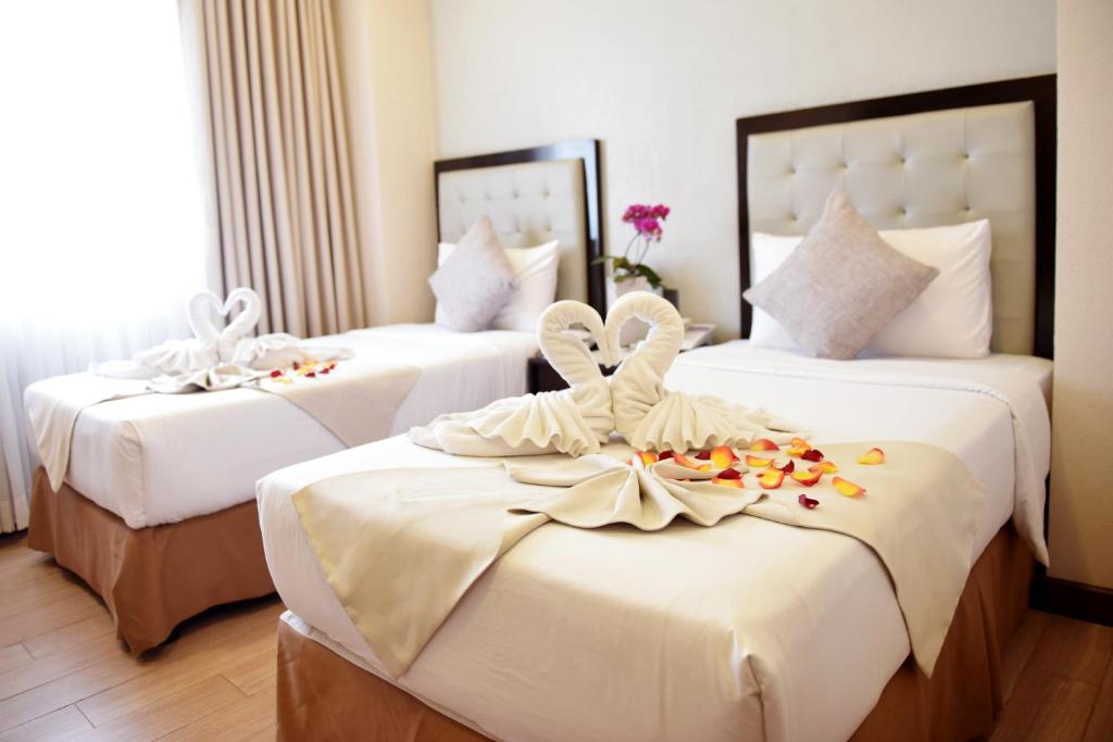 碧瑶Aura One Hotel的酒店客房,配有三张带鲜花的床