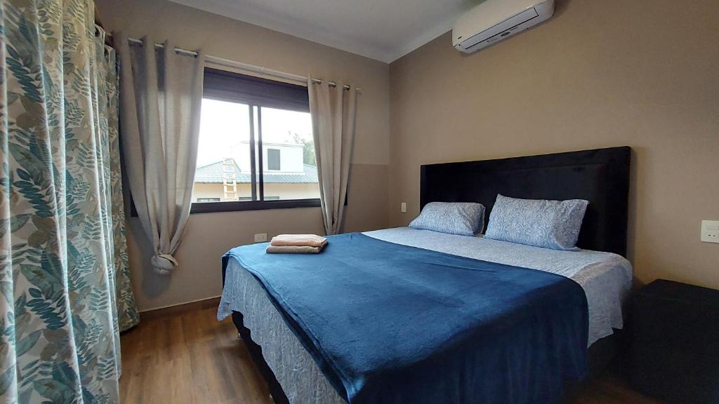 HohenauCasa de huéspedes Mariposa en manantial countryclub的一间卧室配有一张带蓝色毯子的床和窗户。