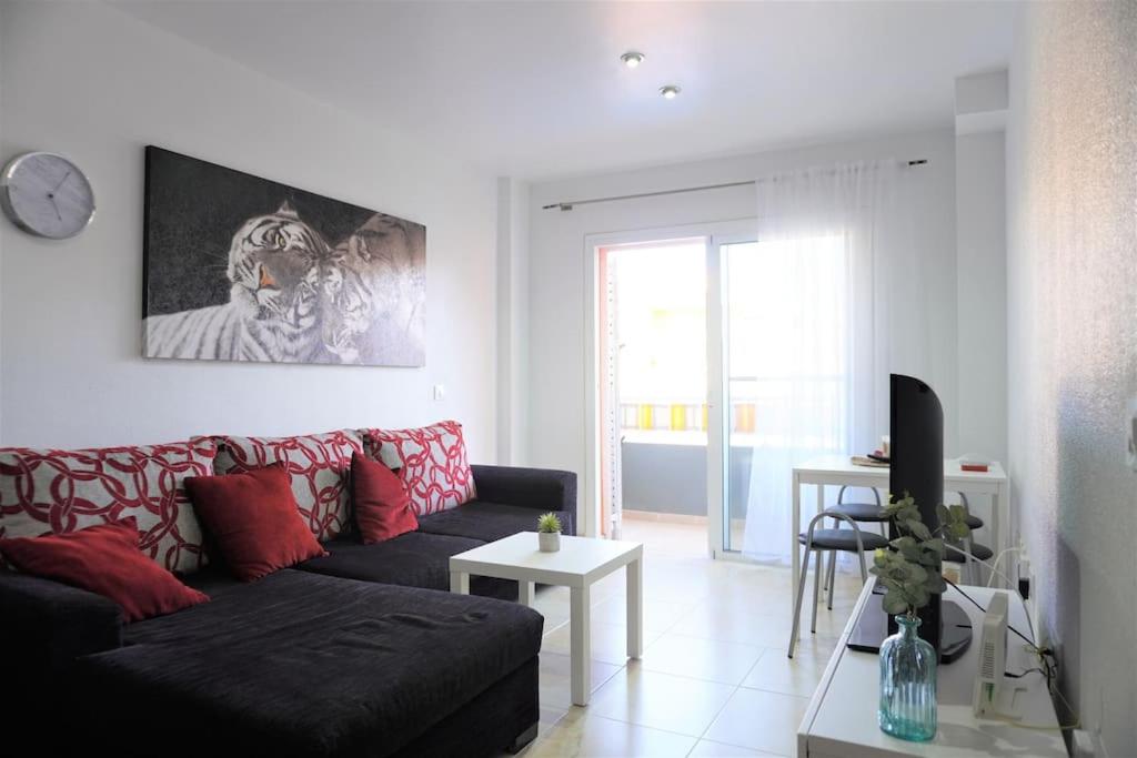 圭马尔港South Coast Apartment的客厅配有黑色沙发和红色枕头
