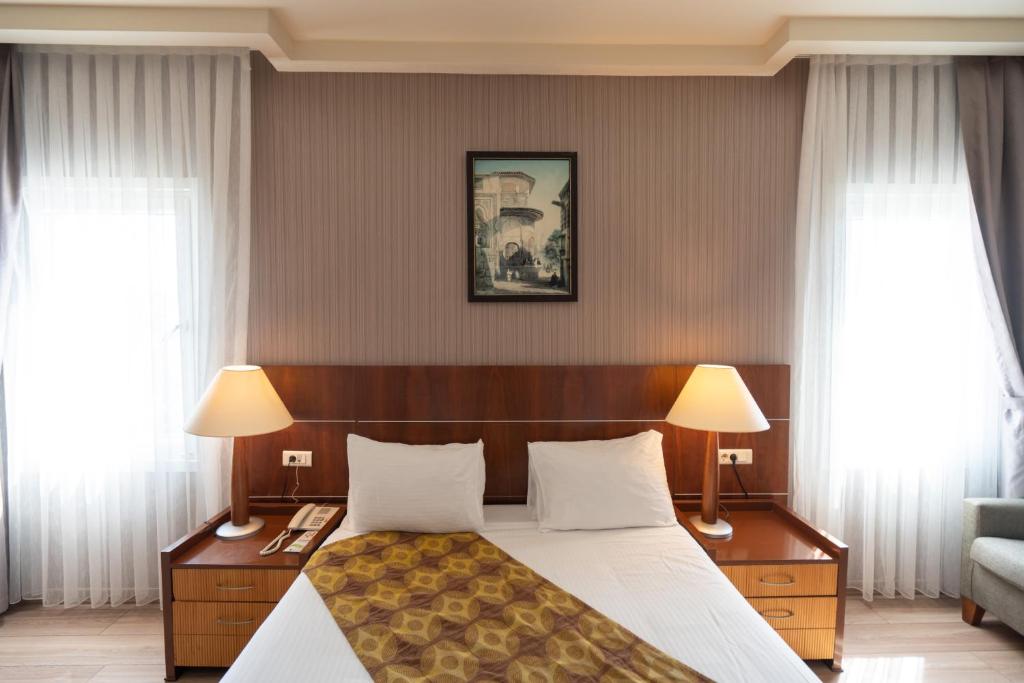 伊斯坦布尔The Green Park Bostancı的一间卧室配有一张带两盏灯的床和两扇窗户。