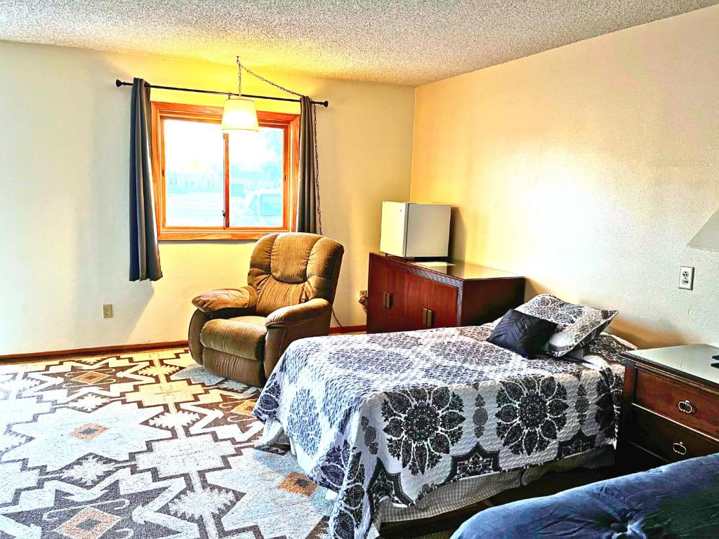 Beaver CityFurnas County Lodging的卧室配有床、椅子和窗户。