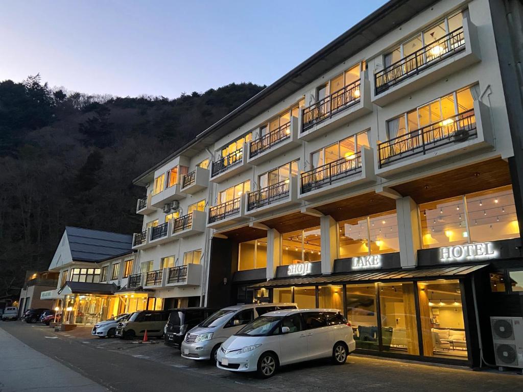 富士河口湖精进湖大酒店的一座大型建筑,前面有汽车停放