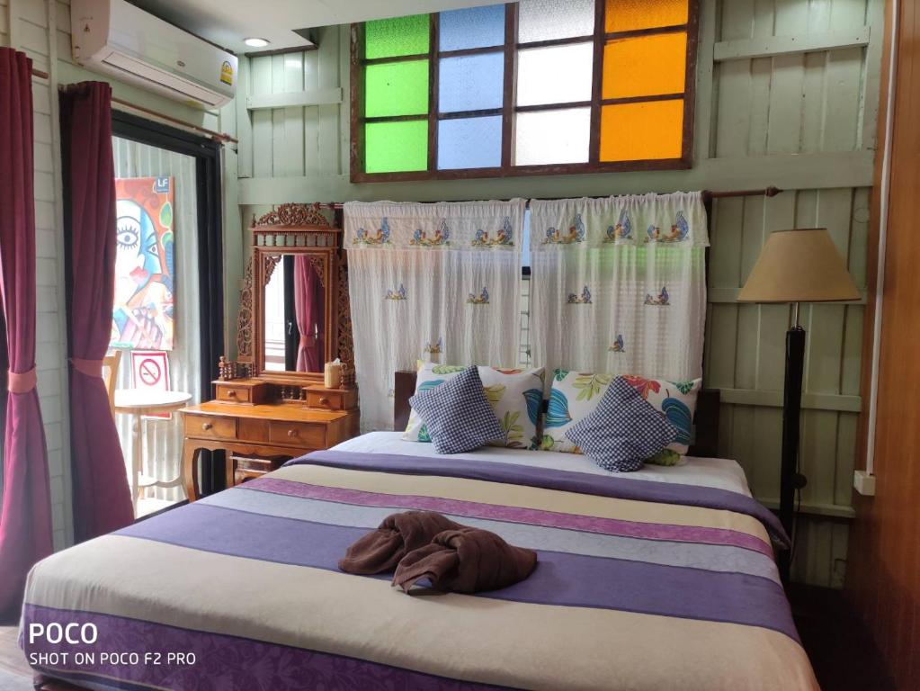 大城tamarind guesthouse的一间卧室设有一张大床和五颜六色的窗户