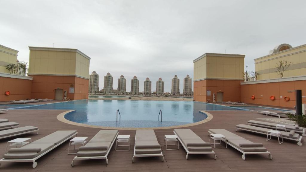 多哈Luxury Sea View Apartment with Amazing Amenities at Pearl Qatar的一座大楼内带躺椅和躺椅的游泳池