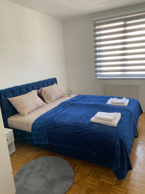 帕莱Apartman Nova Pale的一间卧室配有蓝色的床和毛巾
