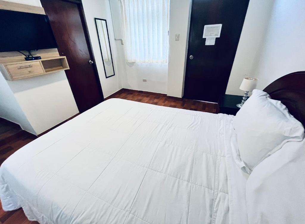 利马Casablanca Lima的一间配有电视的房间里一张大白色的床