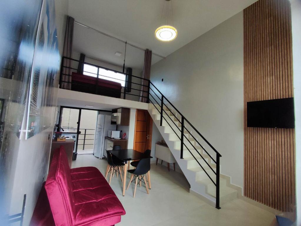 瓜拉图巴GUARATUBA LOFTS的客厅设有楼梯和粉红色的沙发