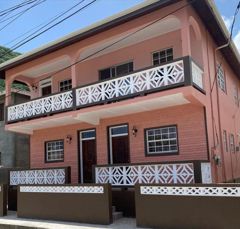 苏弗里耶尔Coco Rose Apartments的粉红色的房子,上面设有阳台