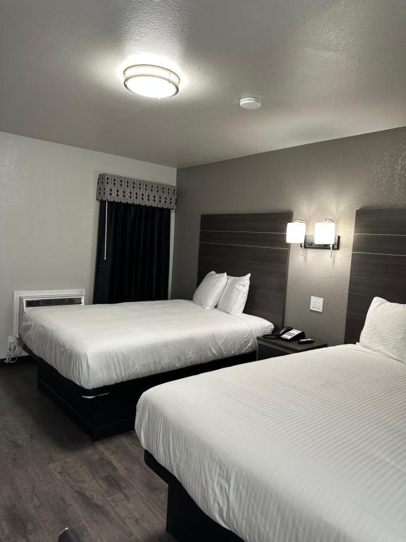 WagonerSleepy Traveler Motel的酒店客房,配有两张带白色床单的床