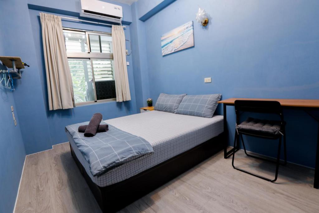 绿岛Green Island Ocean Rhythem dive B&B 綠島海韻民宿的一间卧室设有蓝色的墙壁和一张带书桌的床。