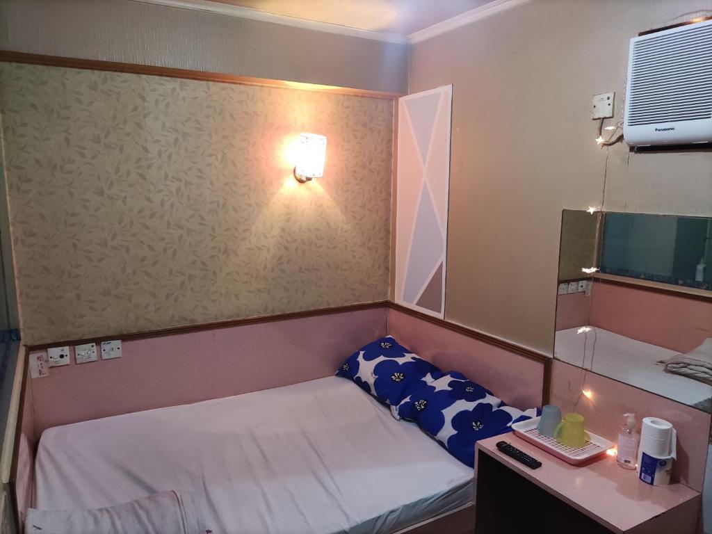 香港嘉湖旅館的小房间设有一张小床和一张书桌