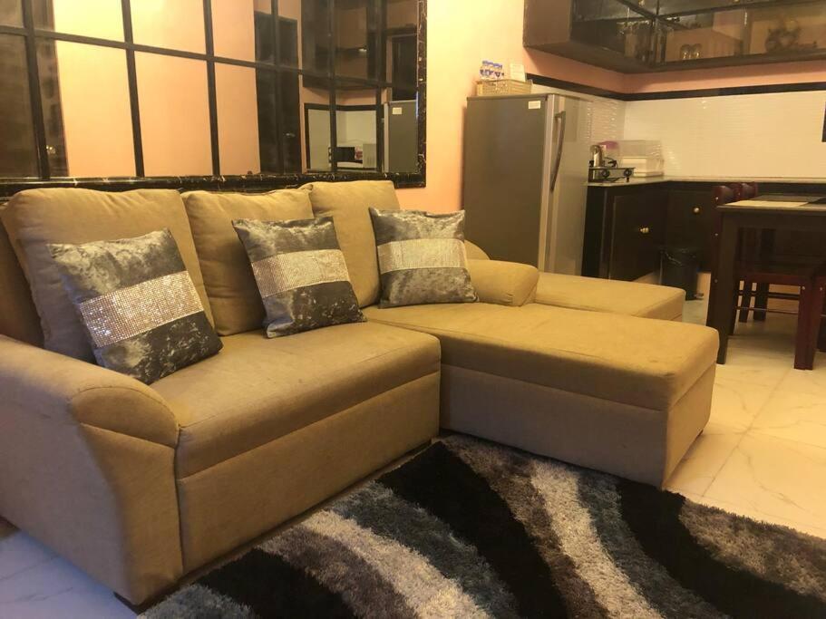 NaicLuzville Residences - C8的客厅里配有带枕头的棕色沙发