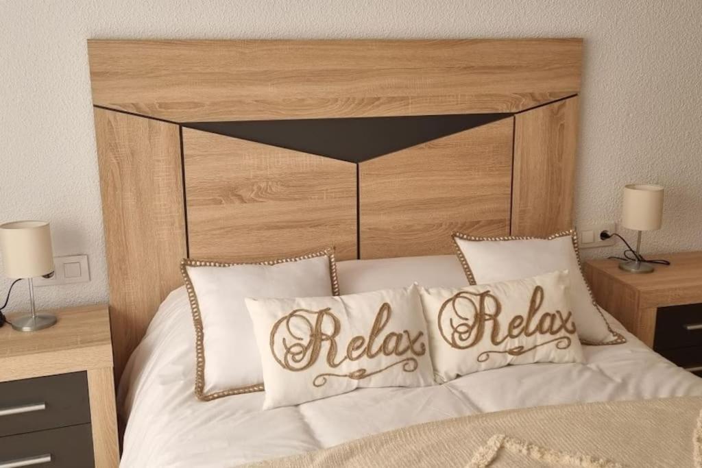 哈恩Piso Puerta del Ángel的一间卧室配有一张带木制床头板和枕头的床。