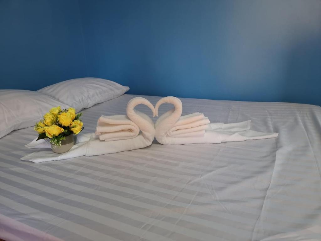清莱หอพักโชคอนันต์的床上的两条天鹅毛巾和鲜花