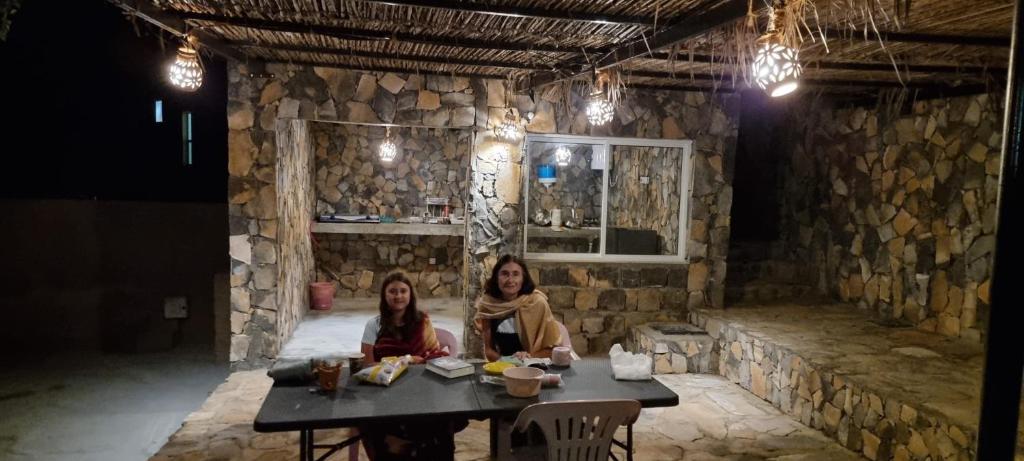 Sa‘ab Banī KhamīsBalcony walk rest house Jabal shams的两个女人坐在石头房的桌子上