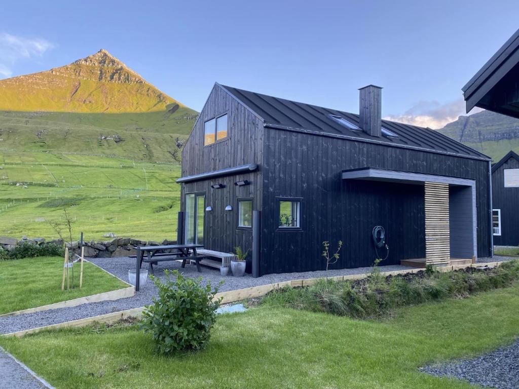 Við GjógvOkkara summarhús við Gjógv - Luxury cottage - Unique location的前面有长凳的黑房子