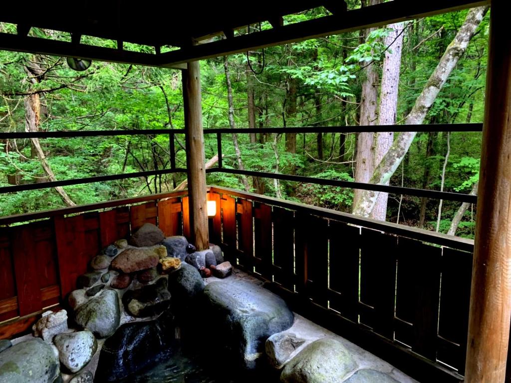 日光一棟貸切 森のお風呂とアウトドアサウナ 日光雪月花的小屋的门廊,里面种有岩石和树木