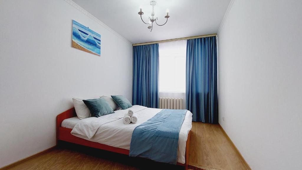 PrigorodnyyАэропорт Астана的一间卧室配有一张带蓝色窗帘的床和一扇窗户