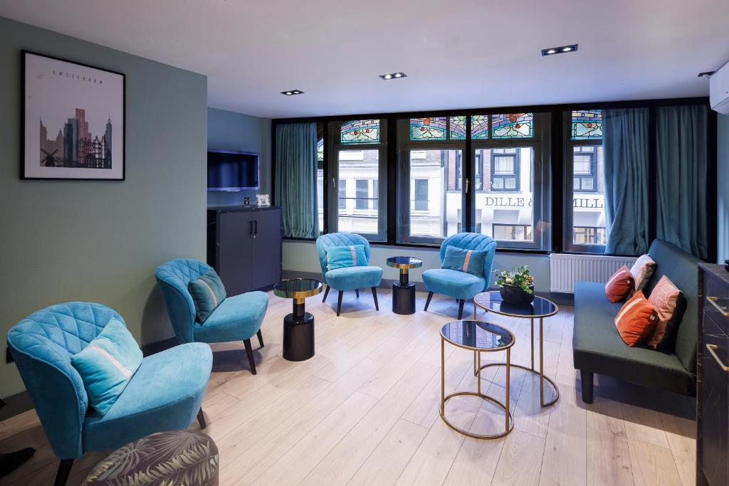 阿姆斯特丹Ciao Papa Hotel Amsterdam Central Station的一间设有蓝色椅子、桌子和窗户的等候室