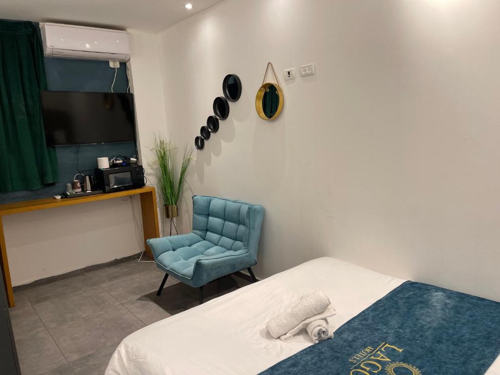 耶路撒冷Lago Suites Hotel的一间卧室配有一张床和一张蓝色椅子