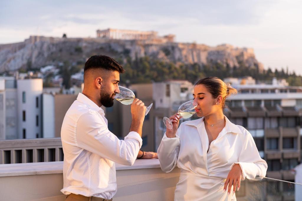 雅典Enattica Suites的男人和女人在阳台上喝葡萄酒