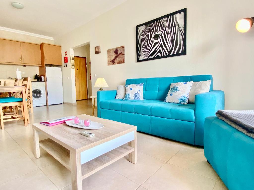 波尔蒂芒Apartamento T1 Flamingo - Portimão - 1,5 km da Praia的客厅配有蓝色的沙发和桌子
