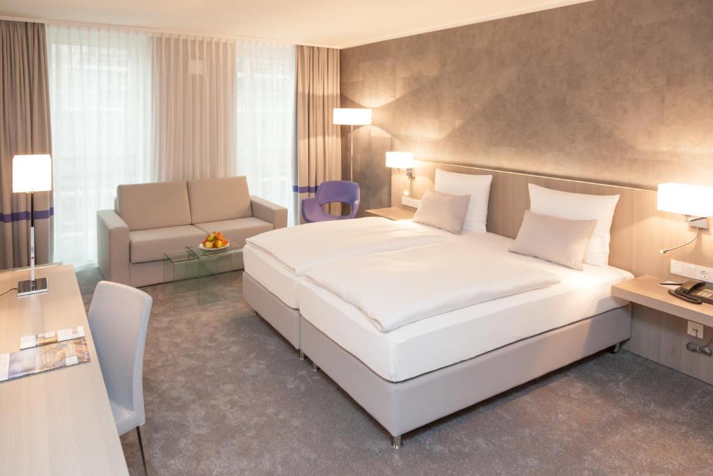 慕尼黑慕尼黑雷莱克萨酒店的卧室配有一张白色的大床和一张沙发。