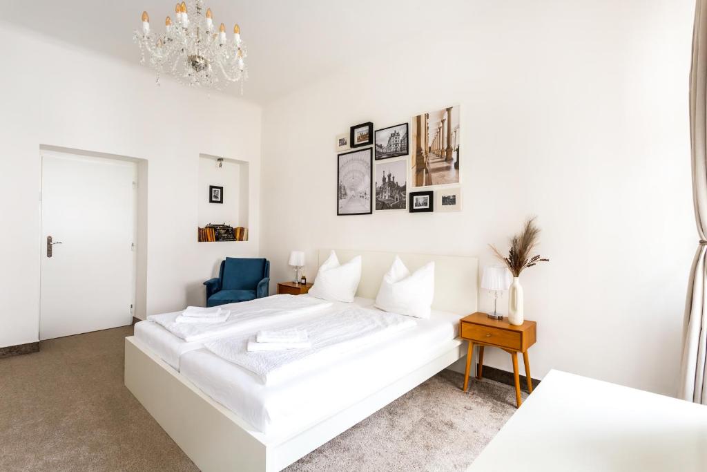 卡罗维发利Apartmá Zeyer 1887的白色卧室配有白色的床和蓝色椅子