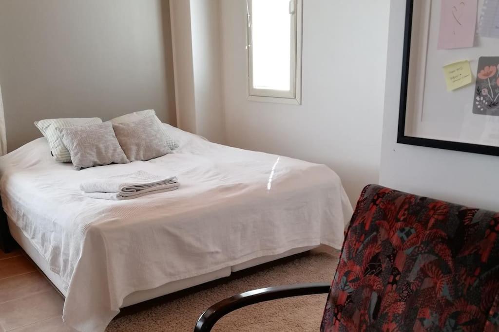 伦派莱Cosy studio apartment near by Ideapark的一间卧室配有一张带白色床单和椅子的床