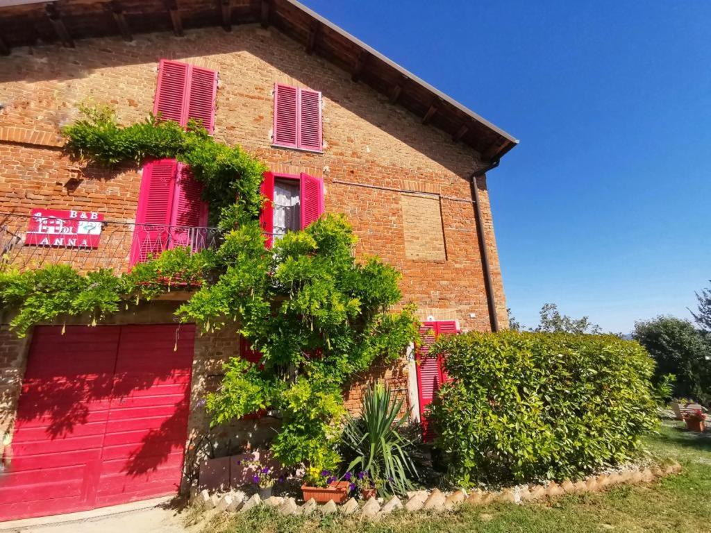 Vaglio SerraA casa di Anna的红砖建筑,有粉红色的百叶窗和植物