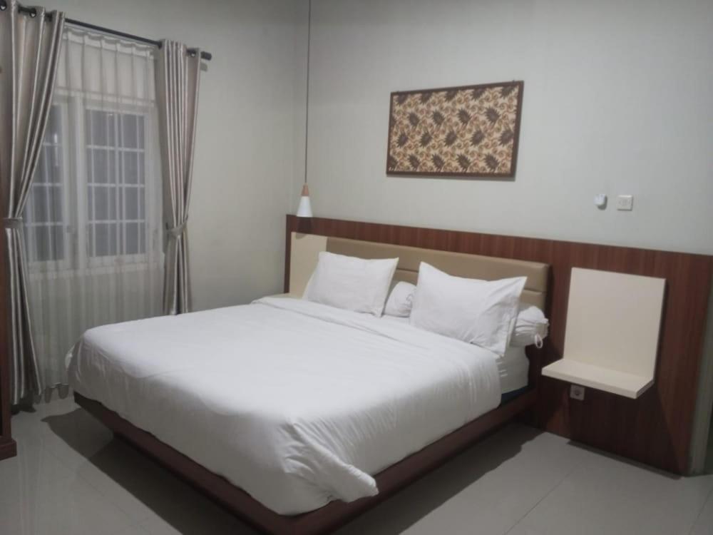 日惹Griya Sambilegi的卧室设有一张白色大床和一扇窗户。