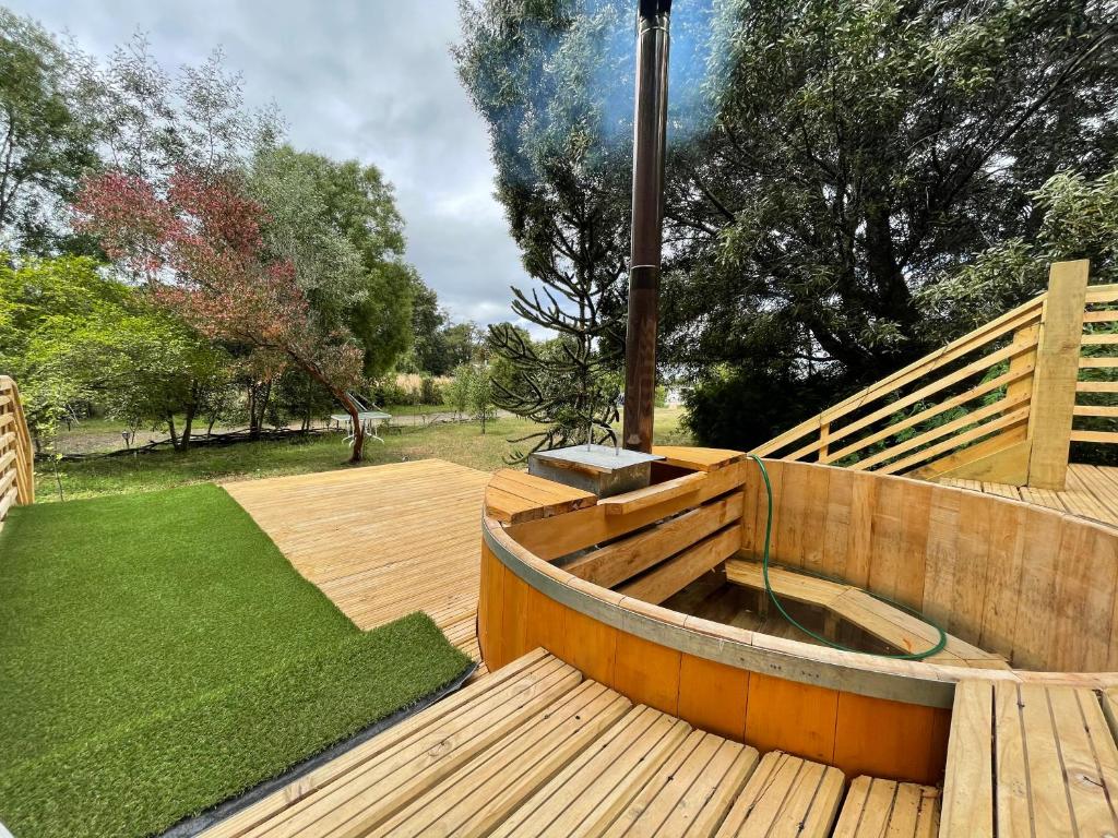 卡斯特鲁Tiny house los zorzales的木甲板设有热水浴池和草坪