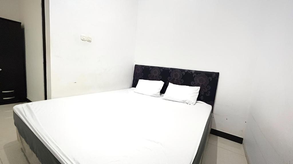 马卡萨OYO 92100 Kost Biru的一张白色的床,上面有两个枕头