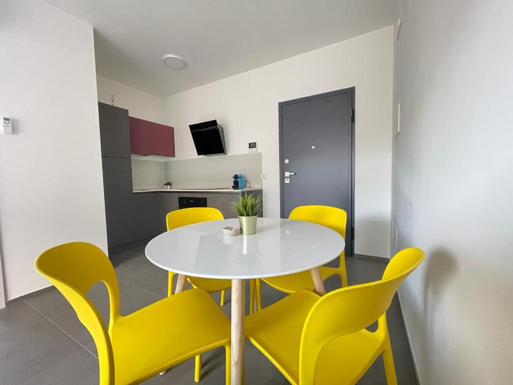托尔托雷托Nuovo a 40 passi dal mare. A casa di “Bicca”的一间设有白色桌子和黄色椅子的用餐室