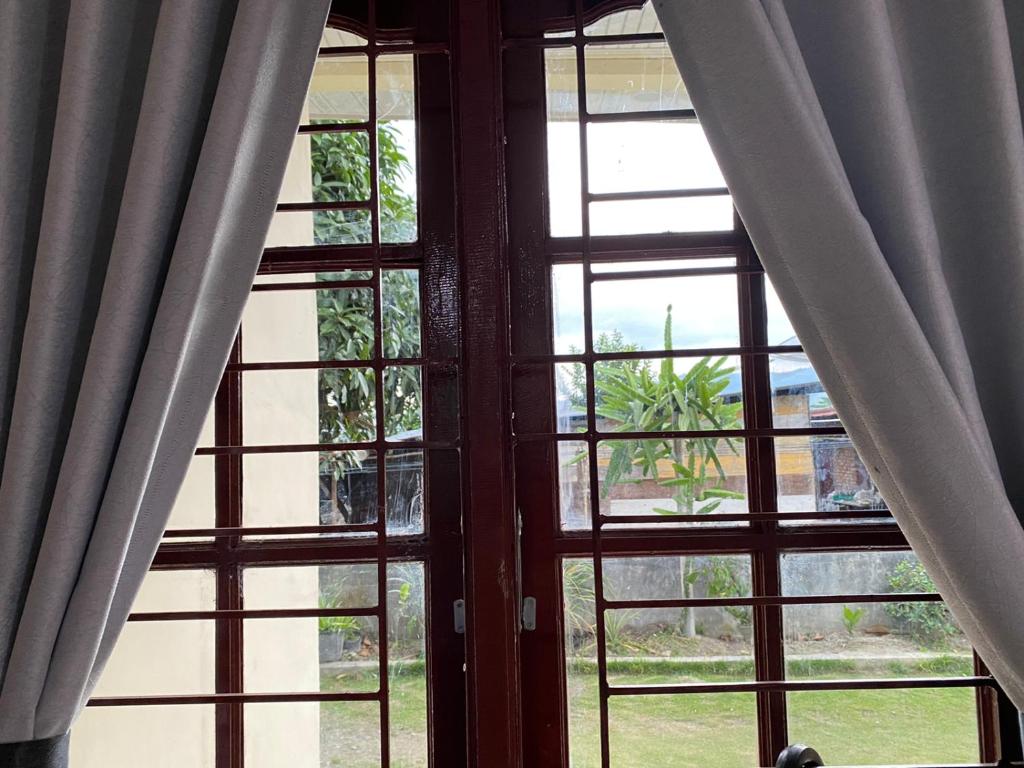巴利盖Paima Homestay的客房内的开放式窗户,配有窗帘