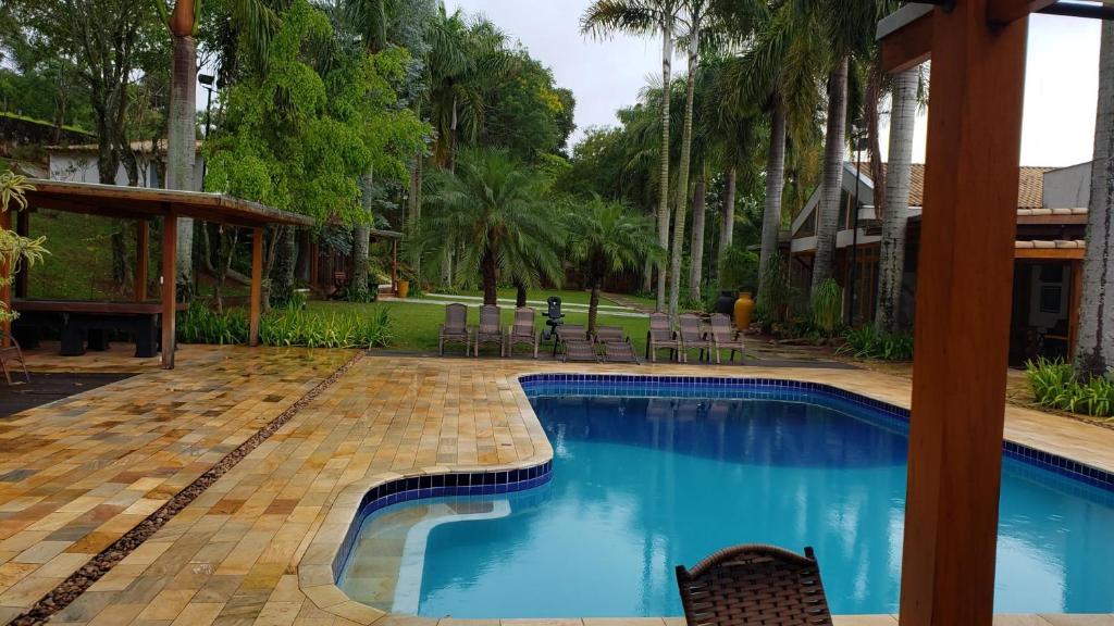 圣罗克OYO Pousada e Hotel Putini的庭院内的游泳池,带椅子和树木