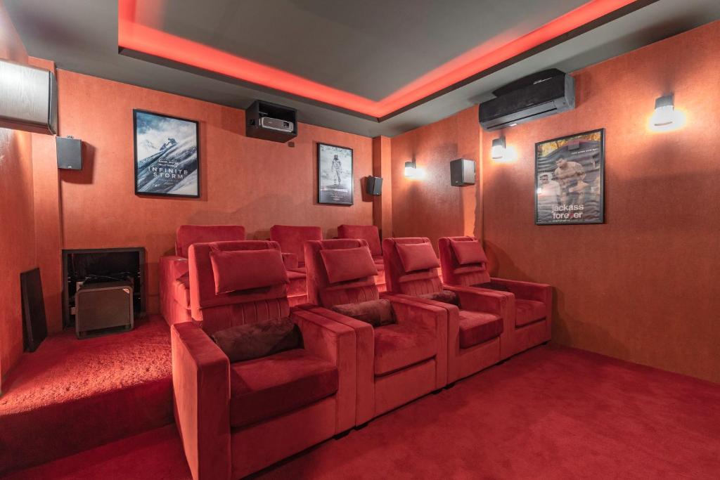 清迈Palm Villa - Award Winning Modern Luxury & Exclusive Villa Resort的电影室设有红色椅子和壁炉
