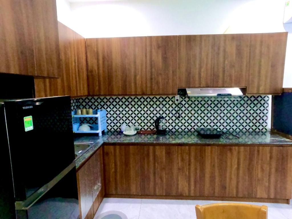 富国Lex Homestay Hotel的厨房配有木制橱柜和黑色冰箱。