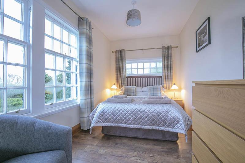德里门Craigievern Cottage的一间卧室设有一张床和两个窗户。