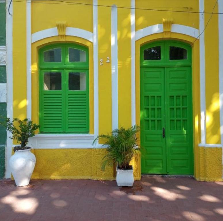 奥林达Casa da Lu的黄色建筑,有绿色门和两盆植物