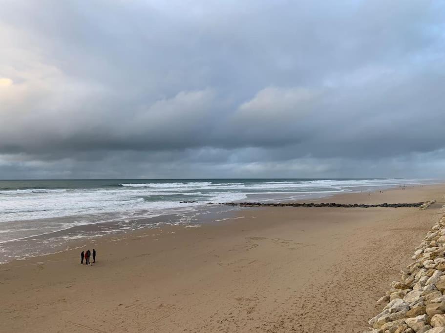 拉卡诺奥肯Agréable T2 Lacanau Ocean bord de mer. Expo sud.的两人在海边的海滩上散步