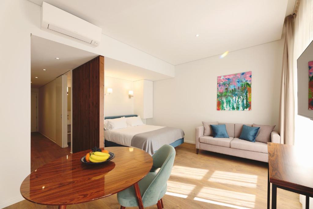波尔图RIBEIRA FLORES 59 Downtown Apartments的酒店客房设有一张桌子、一张床和一张沙发。
